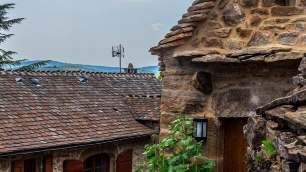 Un bâtiment en pierre avec un toit recouvert de tuiles, une porte en bois et une petite fenêtre.