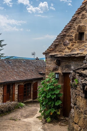 A rustic stone building with a tiled roof, a wooden door, and a small window.
