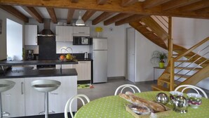 A modern kitchen with wooden beams, a dining area with a green table, and a staircase. - La Maison d'Alphonse 4 people (SAINT LEGER DU MALZIEU)