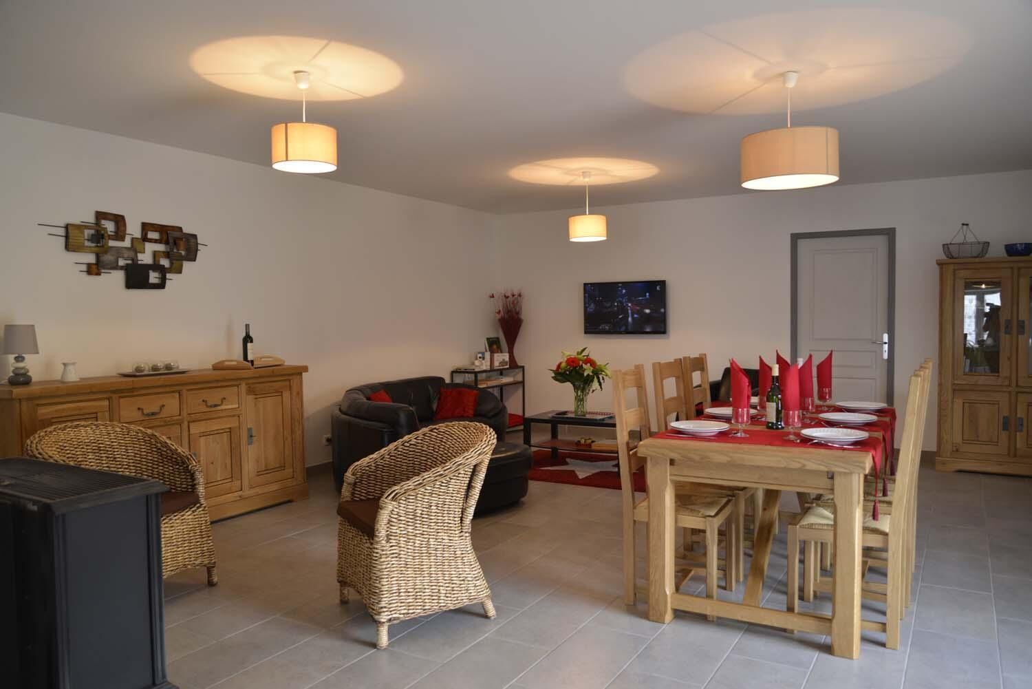 A living room with a dining area, wooden furniture, and pendant lighting.