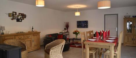 A living room with a dining area, wooden furniture, and pendant lighting.