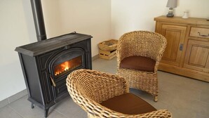 A cozy room with a wood-burning stove, wicker chairs, and a wooden cabinet. - La Maison d'Alphonse 4 people (SAINT LEGER DU MALZIEU)