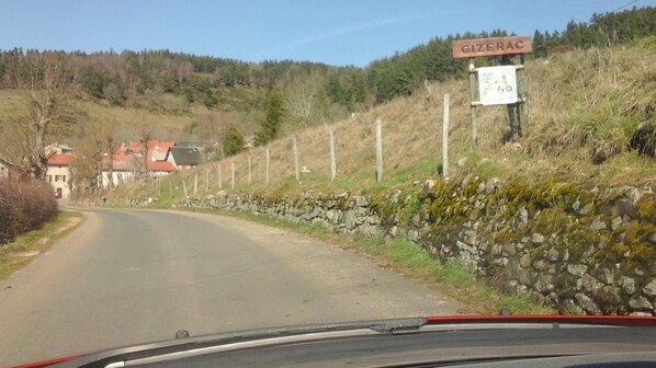 Un camino rural con un muro de piedra y un cartel que indica 'Gizerac'.