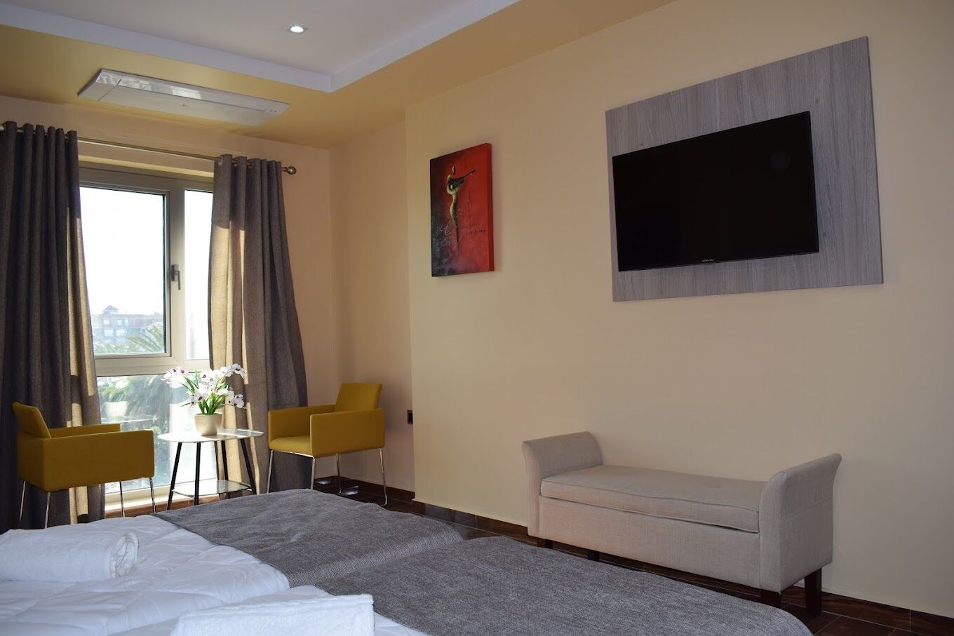 A hotel room with a bed, a sofa, a TV, and a table with chairs.