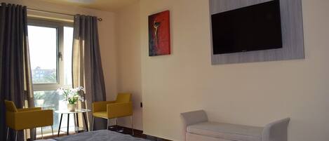 A hotel room with a bed, a sofa, a TV, and a table with chairs.