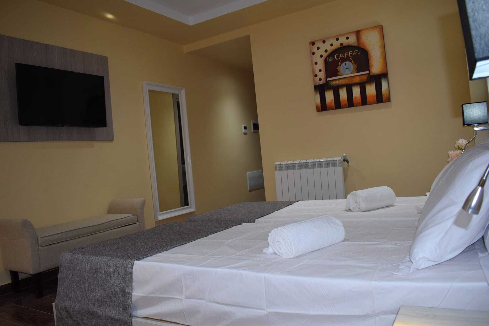 Een hotelkamer met een bed, een stoel, een televisie, een klok en een radiator.