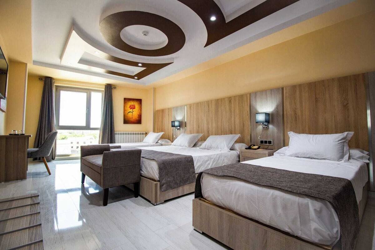 A hotel room with two beds, a desk, and a chair.
