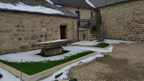 A courtyard with stone buildings, a staircase, and a small garden area with snow.