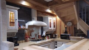 A modern kitchen with a gas stove, wooden cabinets, and a stone wall.
