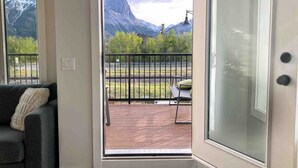 A room with a balcony, a sofa, and a view of mountains. - Modern Mountain Townhouse: private garage/entrance (Canmore)