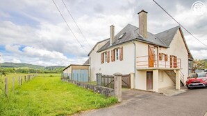 Een tweelaags huis met een garage, een omheinde tuin en een rode auto ervoor geparkeerd.