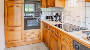 Een keuken met houten kastjes, een magnetron, fornuis en een vaatwasser.