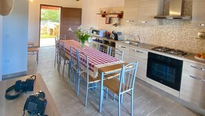 A modern kitchen with a central island, a dining area with a red and white checkered tablecloth, and a wooden ceiling. - Newly built villas located in a quiet hamlet of San Teodoro.  (Schifoni)