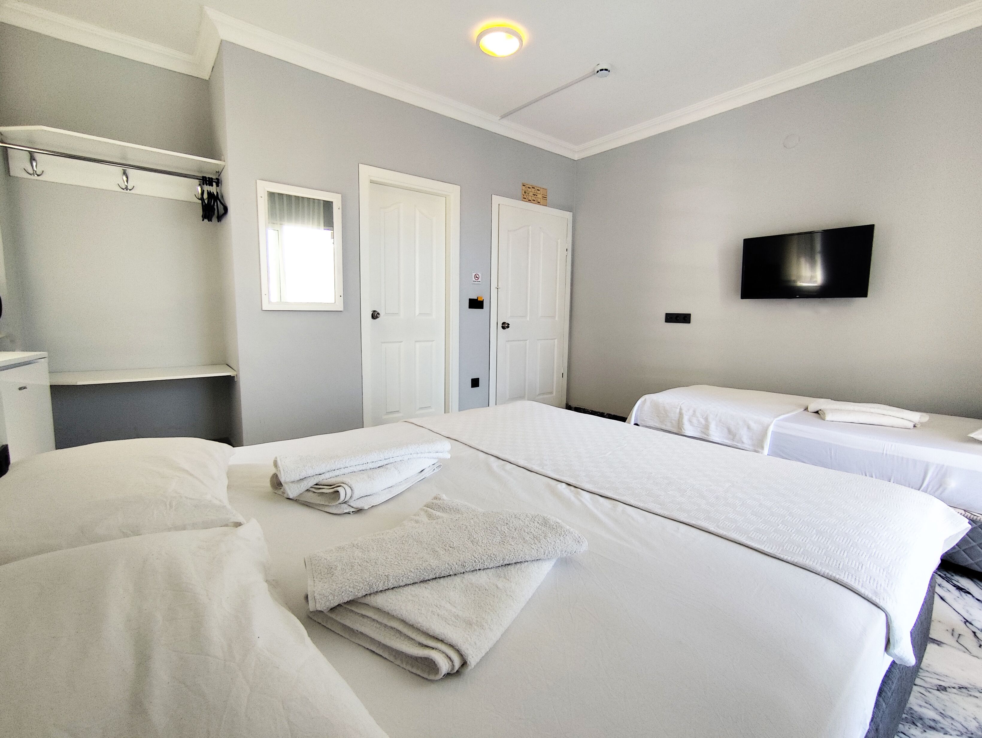 A hotel room with two beds, a TV, a wardrobe, and a bathroom.