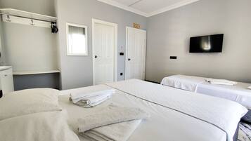 A hotel room with two beds, a TV, a wardrobe, and a bathroom.