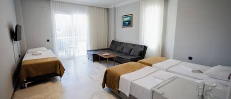 A hotel room with two beds, a sofa, a TV, and a window with curtains.