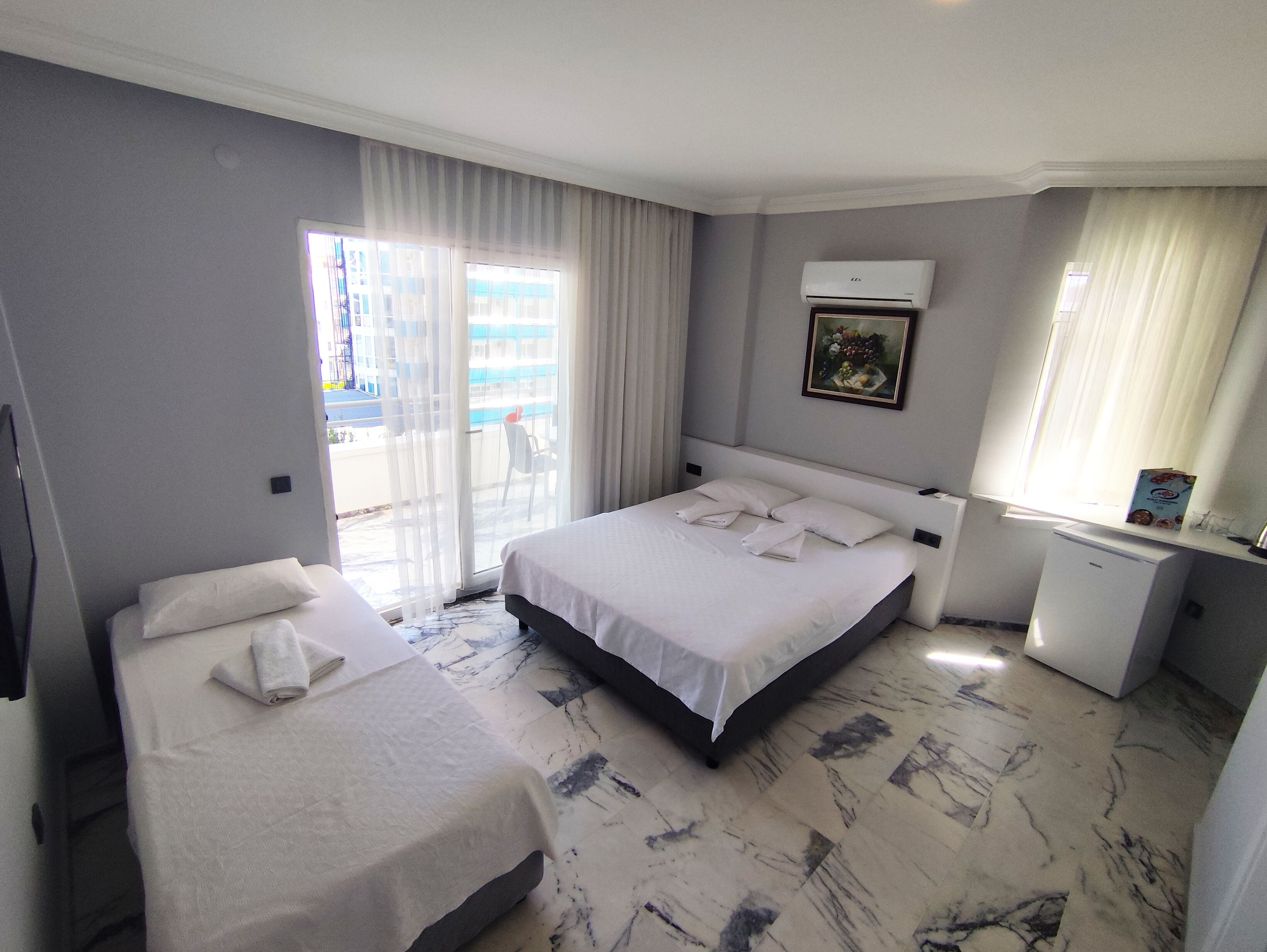 A hotel room with a bed, a desk, and a window with curtains.