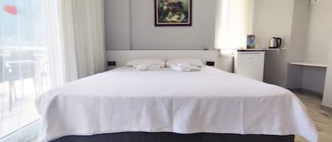 Habitación de hotel con una cama grande, un escritorio pequeño, aire acondicionado y un cuadro en la pared.