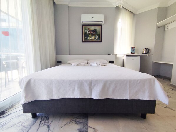 Habitación de hotel con una cama grande, un escritorio pequeño, aire acondicionado y un cuadro en la pared.