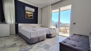 Camera d'albergo con due letti, un divano, un balcone vista e un frigorifero.