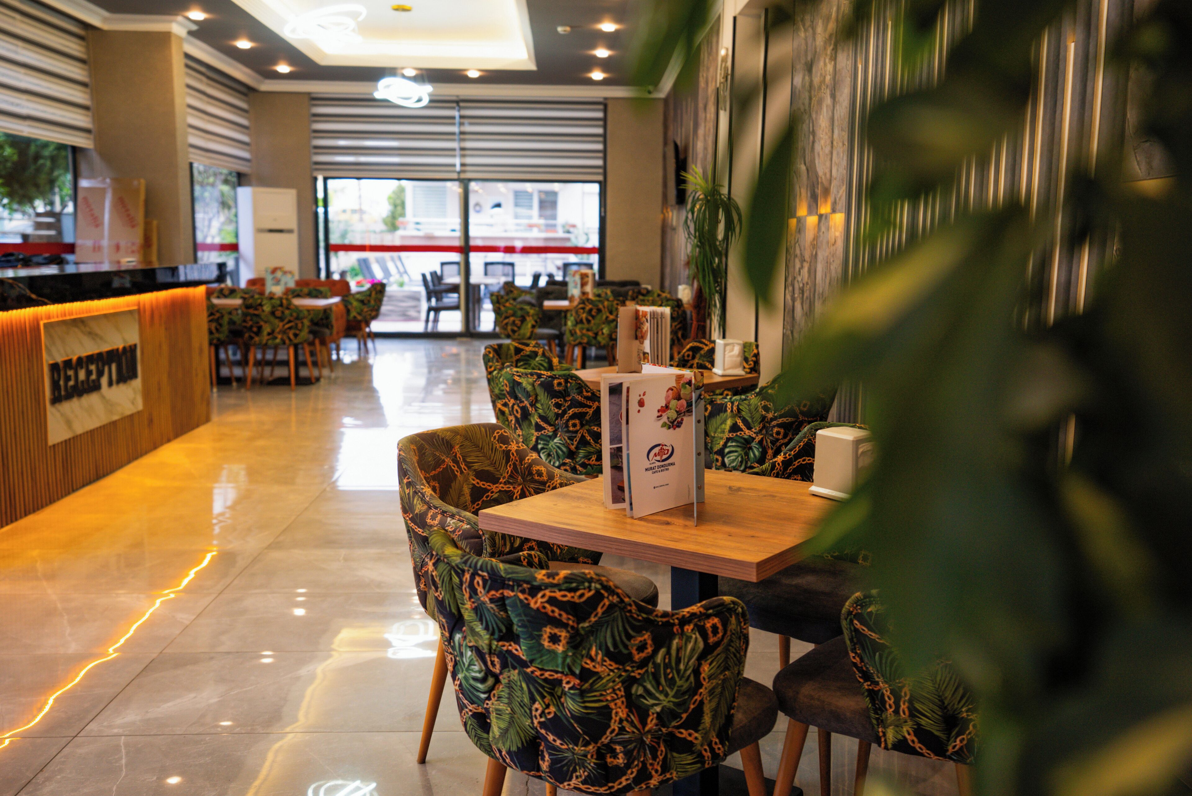 A restaurant with a reception desk, patterned chairs, and a wooden table.