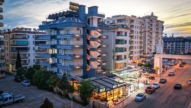 Un hotel a più piani con balconi, un ristorante e un'area parcheggio.