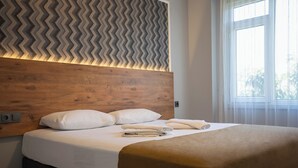 Un letto rifatto con cura, con una testiera in legno, biancheria da letto bianca e una coperta marrone.