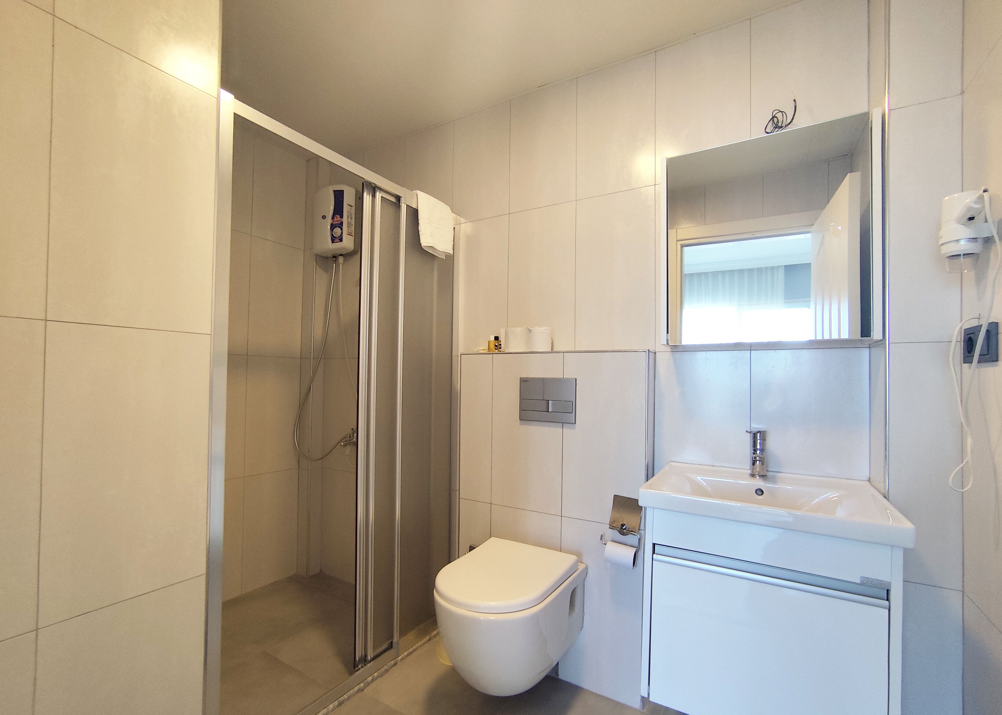 Ein modernes Badezimmer mit Dusche, Toilette, Waschbecken und Spiegel.