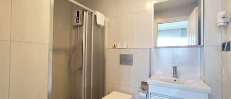 Un baño moderno con ducha, inodoro, lavamanos y espejo.