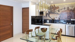 A modern kitchen with a glass dining table, wooden chairs, and a mosaic backsplash. - Dream Cabo Residence with Ocean Views (Cabo San Lucas)