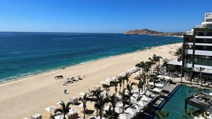 A beach resort with a pool, sun loungers, and umbrellas. - Dream Cabo Residence with Ocean Views (Cabo San Lucas)