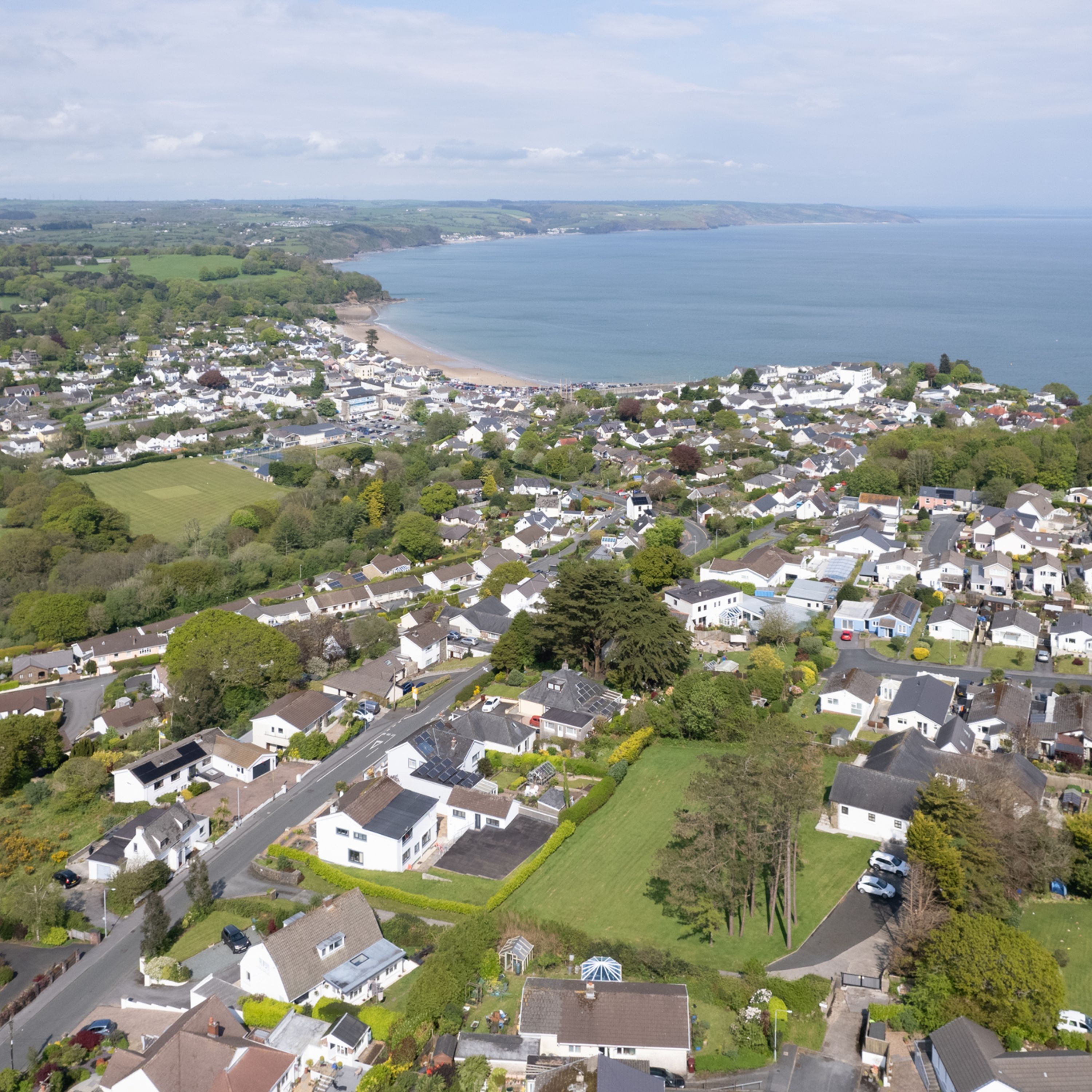 An aerial view of a coastal residential area with houses, roads, and a beach.