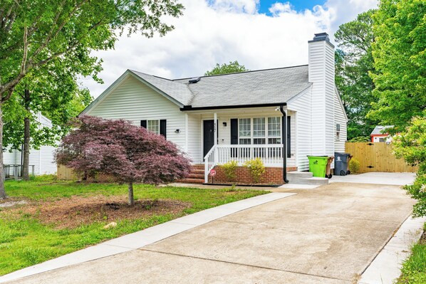 A single-story house with a front porch, a chimney, and a small front yard. - Modern Charm in Holly Springs: New Transformed Home (Holly Springs)