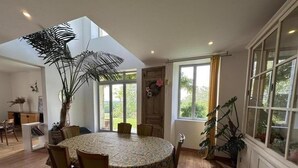 Un coin repas avec une table ronde, des chaises et des plantes en pot.