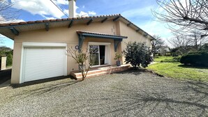 A single-story house with a garage, a small porch, and a gravel driveway. - Le Gîte du Sequé - Saint Pandelon (SAINT PANDELON)