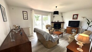 A living room with a fireplace, a television, a sofa, a coffee table, and a lamp. - Le Gîte du Sequé - Saint Pandelon (SAINT PANDELON)