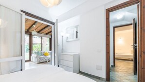 A bedroom with a bed, a white dresser, a mirror, and a view of an outdoor area with a sofa and a window. - Fiorenza's charming beach house (Pula)