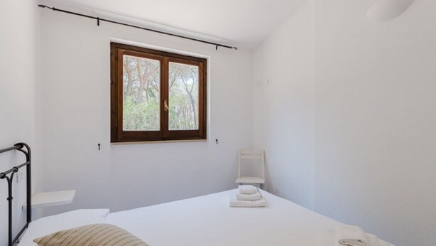 Una camera da letto con un letto, una finestra, un comodino e una sedia.