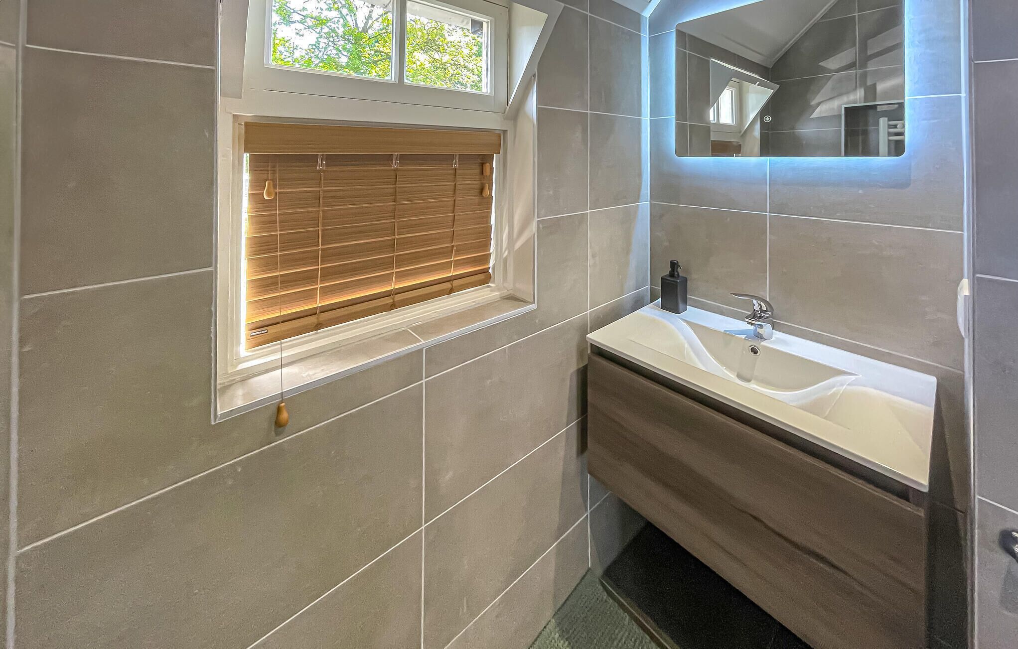 A modern bathroom with a large window, a sink, and a mirror.