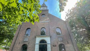 A brick building with a clock tower, arched windows, and a central entrance. - Cozy home in Noordscheschut with WiFi (Noordscheschut)