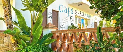 A cafe with a white exterior and a sign that reads "Cafe Snack Kasaba".