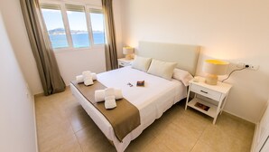 A neatly made bed with a brown blanket, a bedside lamp, and a book on the nightstand. - Seaside penthouse apartment with sea views and swimming pool (Calpe)