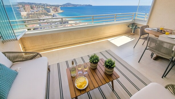 A balcony with a view of the sea, a dining area with a table, chairs, and a potted plant. - Seaside penthouse apartment with sea views and swimming pool (Calpe)