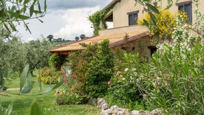 Una casa rustica con un giardino, un muro in pietra e una recinzione in legno.