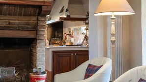 Un accogliente soggiorno con camino, una poltrona confortevole e un'area pranzo sullo sfondo.