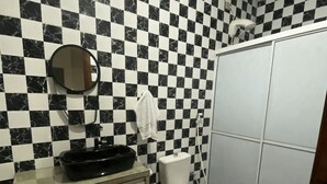 A bathroom with a checkered floor and walls, a toilet, a sink with a mirror, and a towel hanging on the wall.
