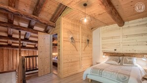 Una habitación de cabaña de madera con una cama, una mesita y una lámpara colgante.