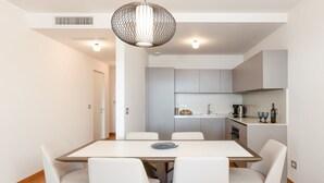 A modern kitchen with grey cabinets, a dining table with white chairs, and a pendant light.