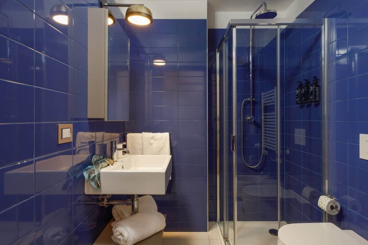 Een moderne badkamer met een douchecabine van glas, een wit wastafelmeubel en een spiegel.