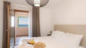 A hotel room with a bed, a nightstand, a lamp, a view of the outdoors, and a large window.